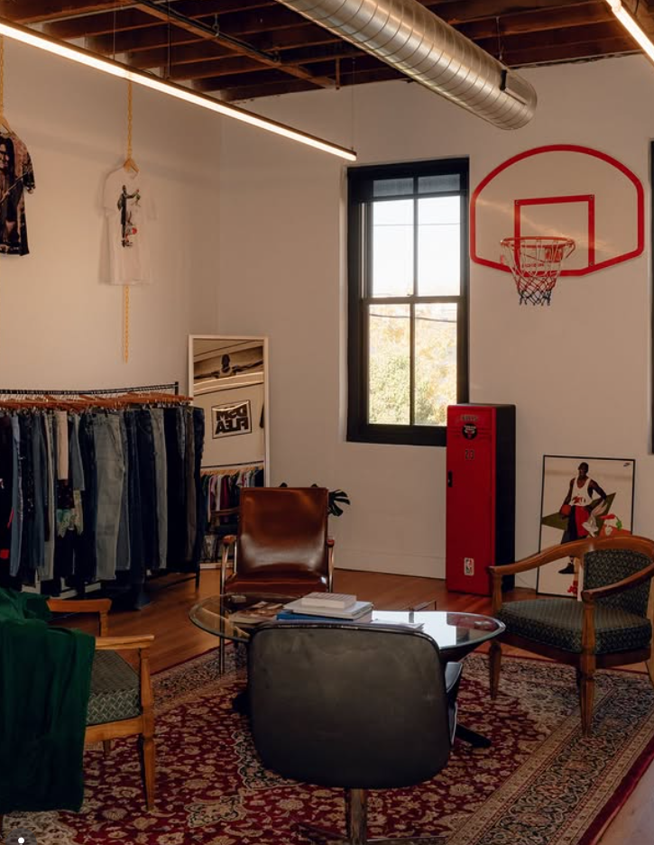 A bustling indoor vintage flea market with string lights and clothing racks